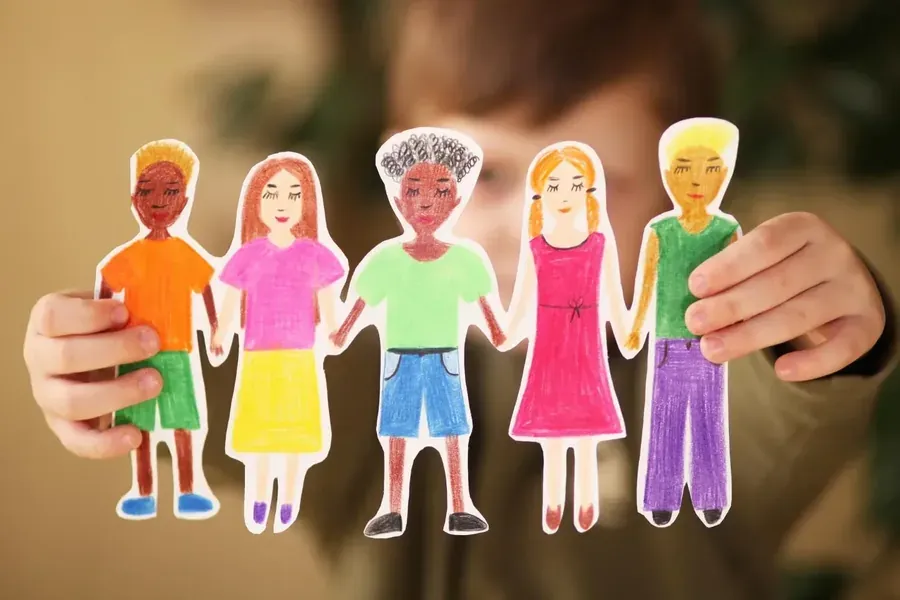 Enfant tenant une guirlande de cinq personnages en papier colorés et dessinés