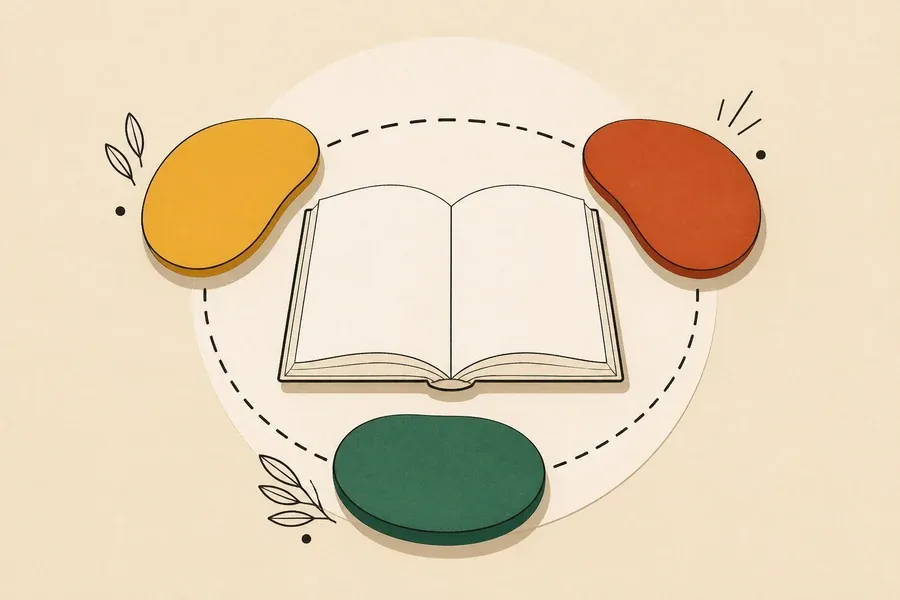 Un livre crème est entouré de trois pierres colorées et arrondies.